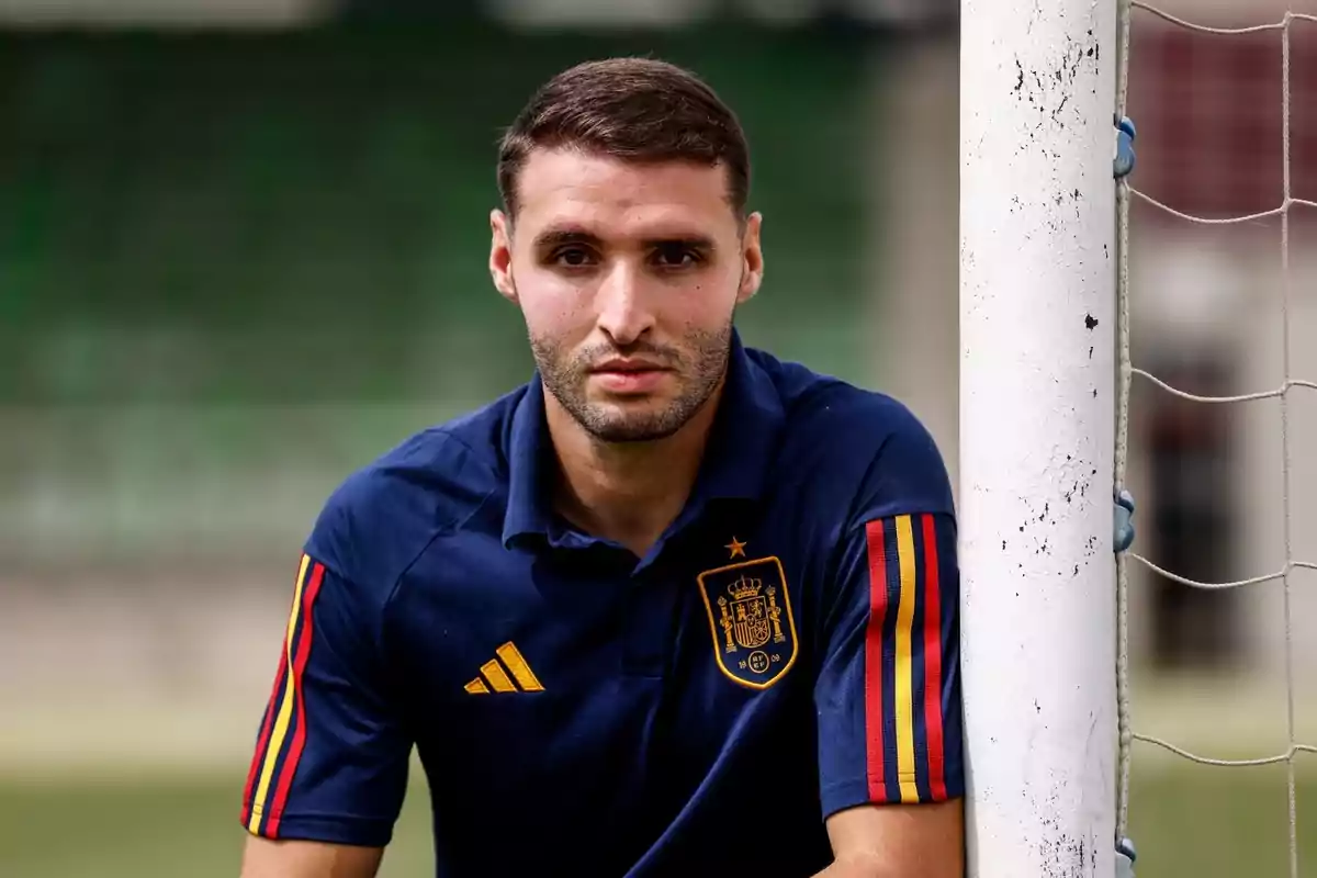 Hombre con camiseta de la selección española de fútbol junto a un poste de la portería.
