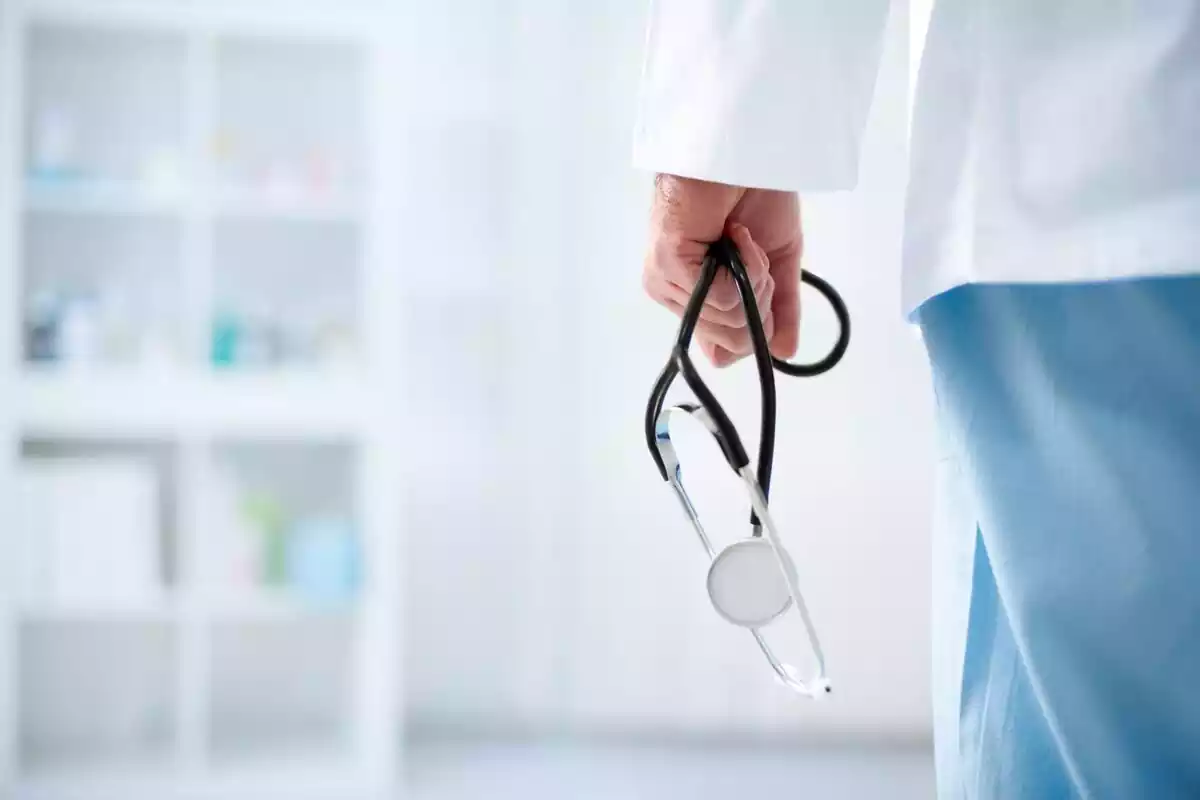Mano de un doctor sosteniendo un estetoscopio en una sala de hospital