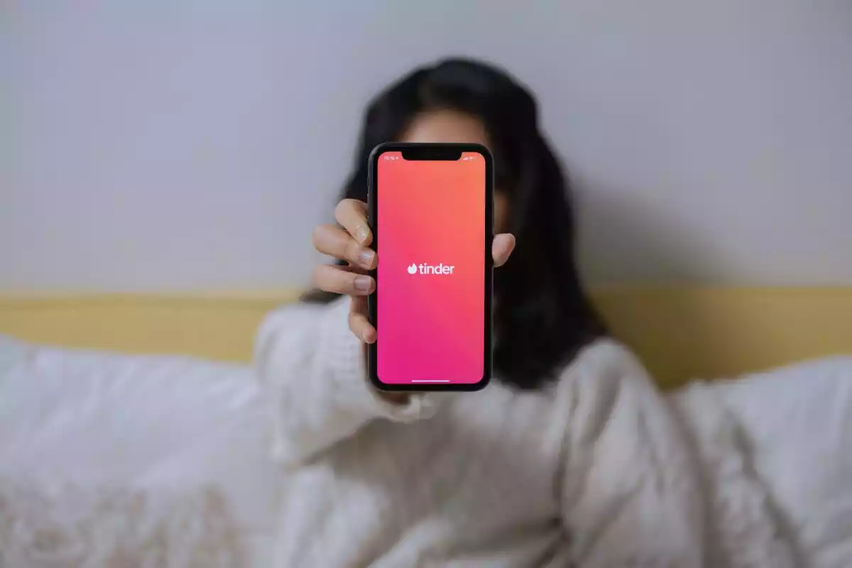 Mujer sosteniendo el móvil con la aplicación de Tinder abierta