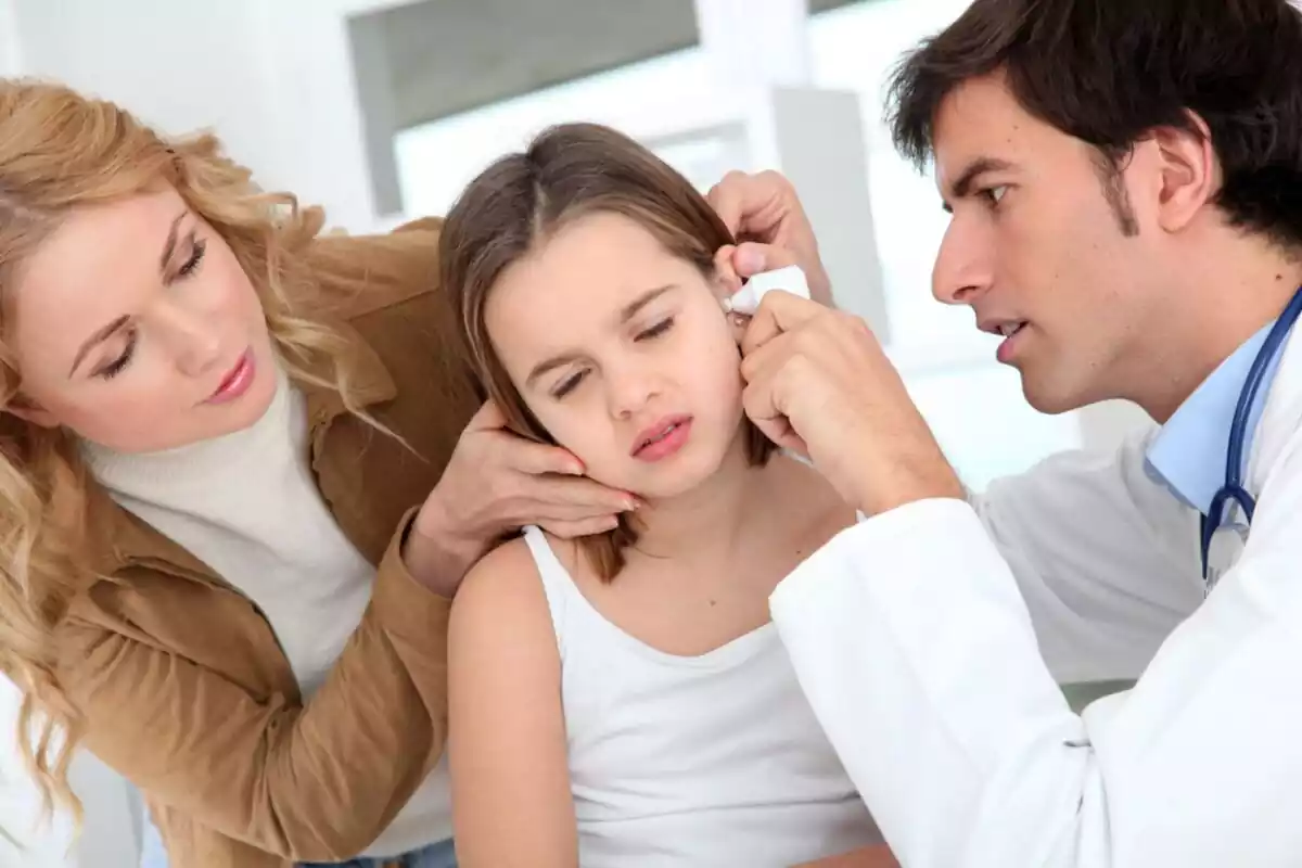 Doctor mirando la oreja de una niña