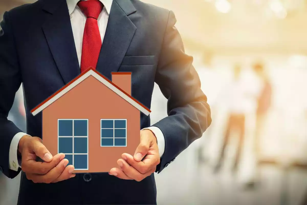 Un hombre sosteniendo una maqueta de una casa simulando ser una hipoteca