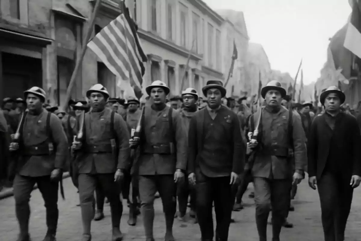 Soldados afroamericanos marchan en formación por una calle durante la Primera Guerra Mundial llevando banderas y uniformes históricos. Soldados afroamericanos marchan en formación por una calle durante la Primera Guerra Mundial llevando banderas y uniformes históricos.