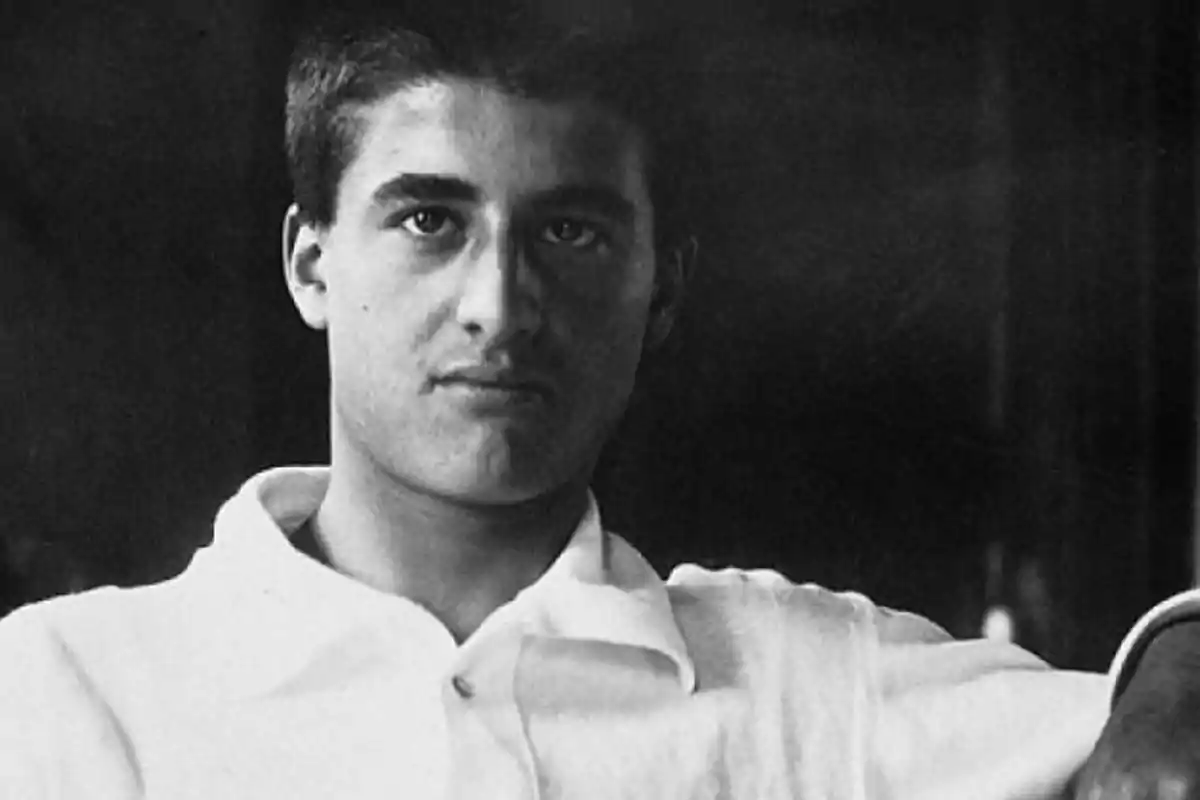 Joven con cabello corto y camisa clara mirando a la cámara en una fotografía en blanco y negro Joven con cabello corto y camisa clara mirando a la cámara en una fotografía en blanco y negro