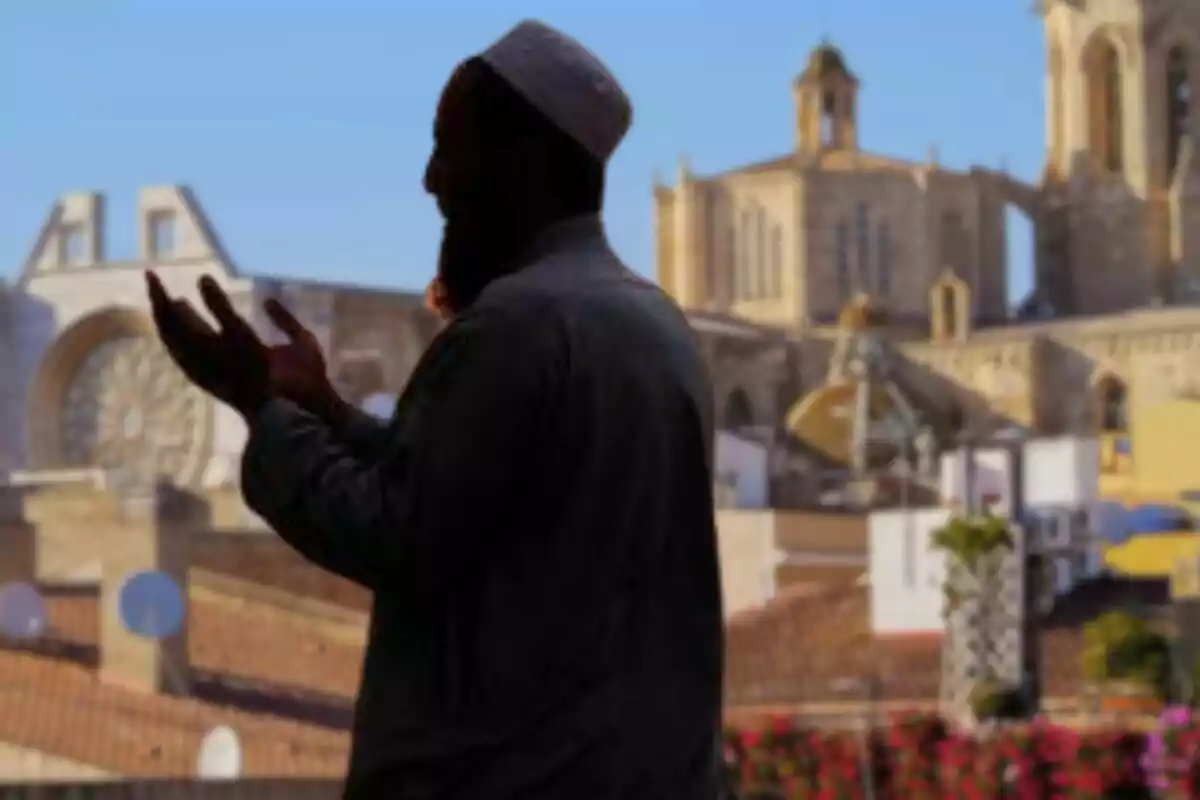 Hombre de perfil rezando al aire libre con una iglesia antigua de fondo en un día soleado