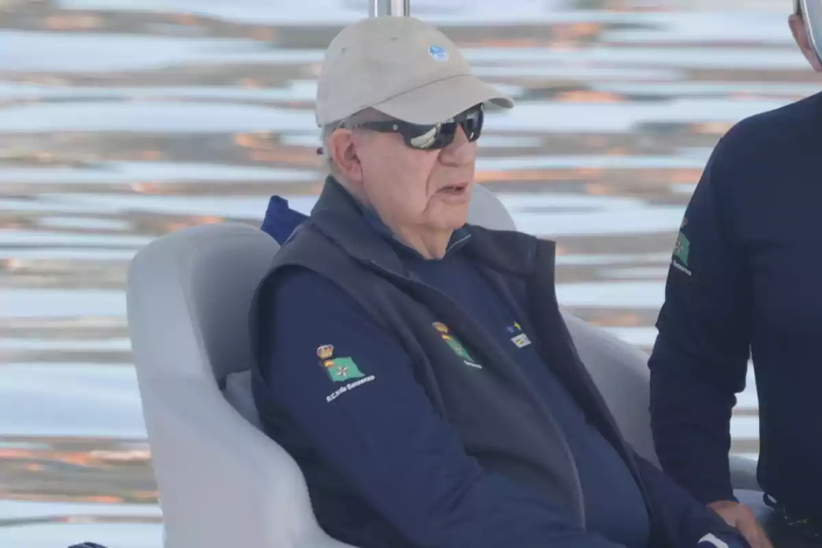 Juan Carlos I con gorra y gafas de sol sentado en un bote sobre el agua Juan Carlos I con gorra y gafas de sol sentado en un bote sobre el agua