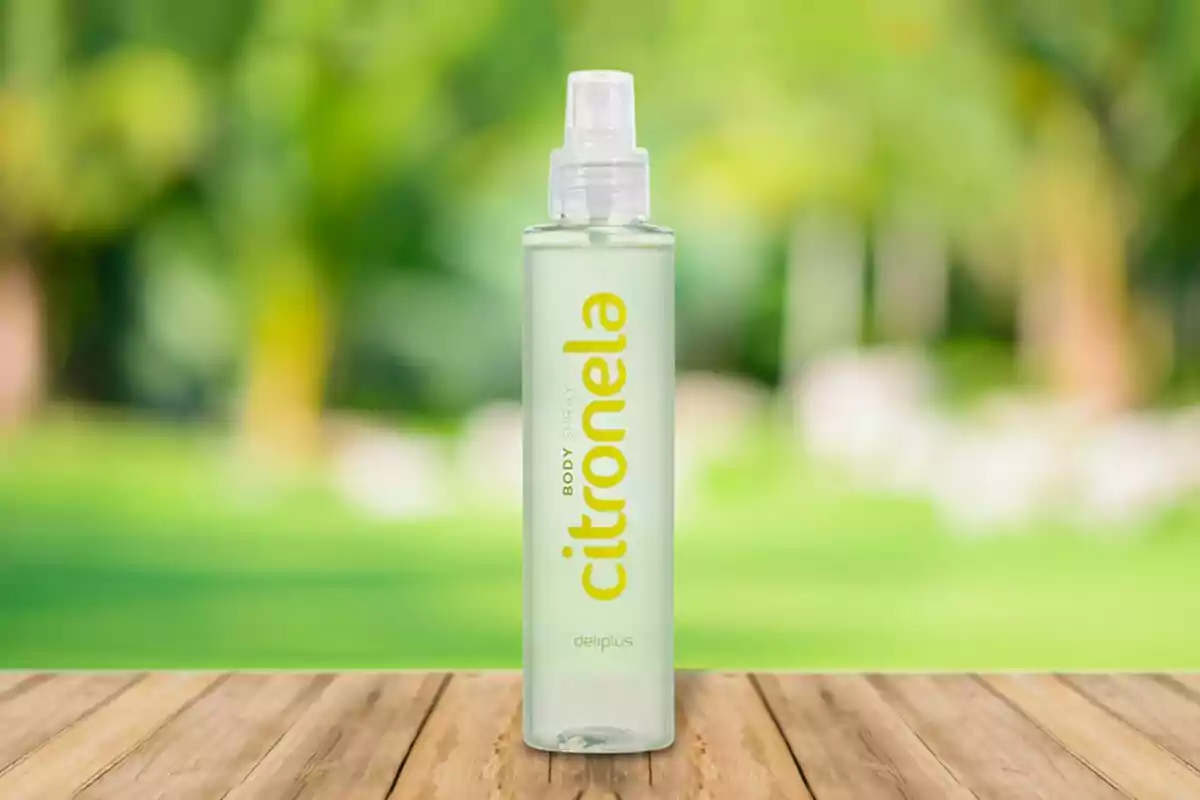 Botella de spray de citronela sobre una mesa de madera con fondo desenfocado de jardín verde Botella de spray de citronela sobre una mesa de madera con fondo desenfocado de jardín verde