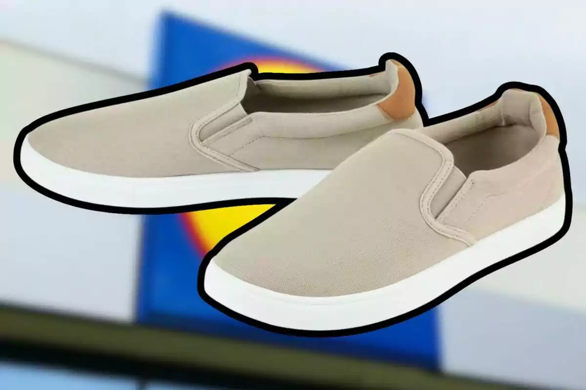 Un par de tenis beige tipo slip-on con suela blanca y detalle marrón en el talón, sobre un fondo desenfocado con colores azul y amarillo. Un par de tenis beige tipo slip-on con suela blanca y detalle marrón en el talón, sobre un fondo desenfocado con colores azul y amarillo.