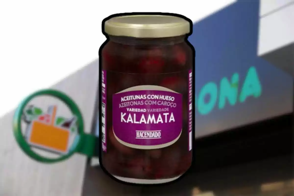 Frasco de aceitunas Kalamata de la marca Hacendado frente a una tienda Mercadona desenfocada. Frasco de aceitunas Kalamata de la marca Hacendado frente a una tienda Mercadona desenfocada.