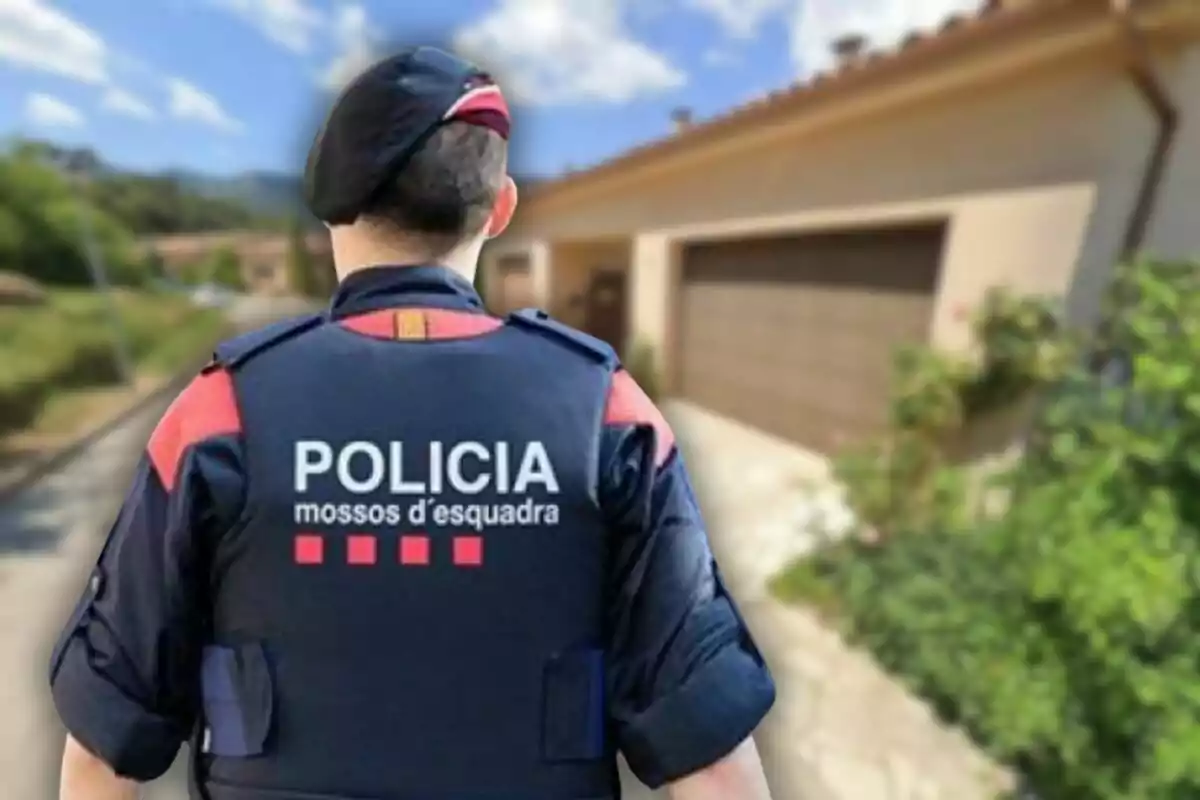 Agente de los Mossos d'Esquadra de espaldas frente a una casa en una zona residencial