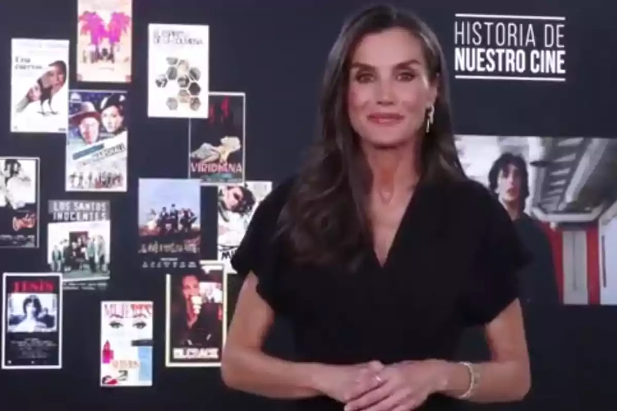 La reina Letizia, vestida de negro, posando frente a un fondo con carteles de películas para felicitar al programa 'Historia de nuestro cine'