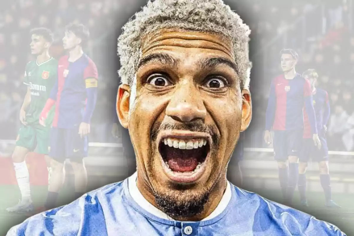 Hombre con cabello rubio platinado y expresión de sorpresa o emoción en primer plano con fondo difuminado de jugadores de fútbol en un estadio