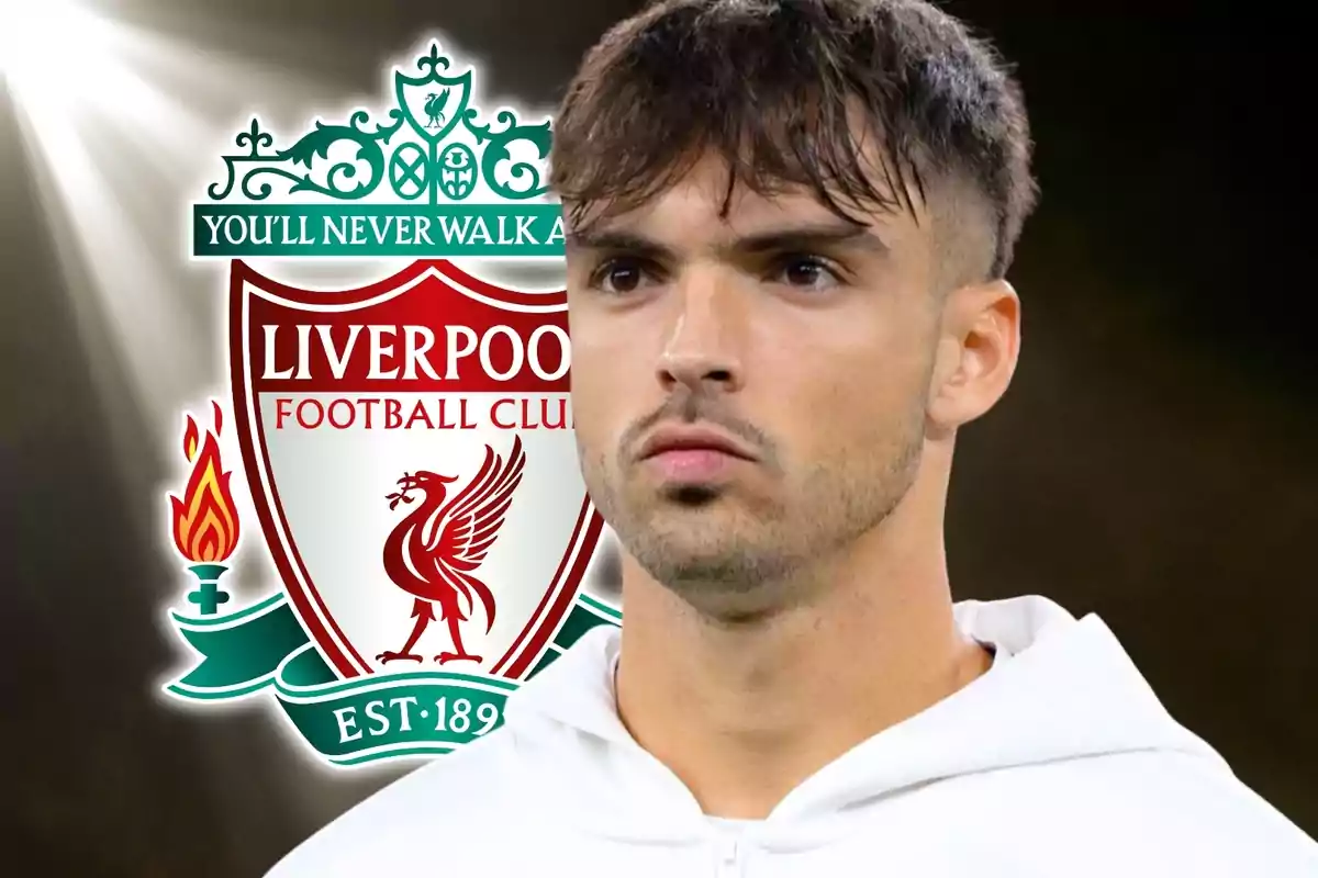 Un futbolista con expresión seria aparece en primer plano con el escudo del Liverpool Football Club de fondo.
