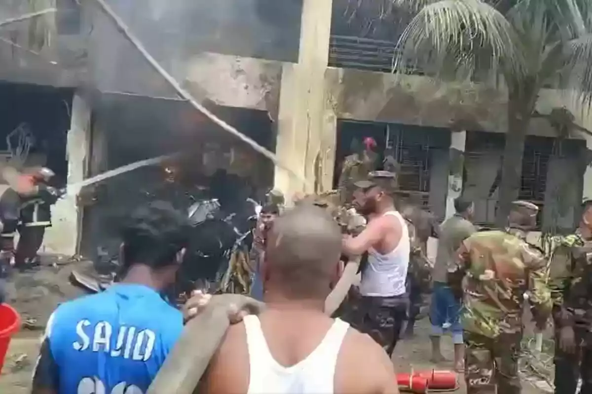 Varias personas, entre ellas bomberos y militares, trabajan para apagar un incendio en un edificio mientras se observa humo saliendo del lugar. Varias personas, entre ellas bomberos y militares, trabajan para apagar un incendio en un edificio mientras se observa humo saliendo del lugar.