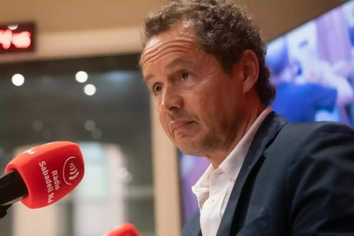 Hombre de cabello rizado y canoso hablando frente a un micrófono rojo de Ràdio Sabadell en un estudio de radio Hombre de cabello rizado y canoso hablando frente a un micrófono rojo de Ràdio Sabadell en un estudio de radio