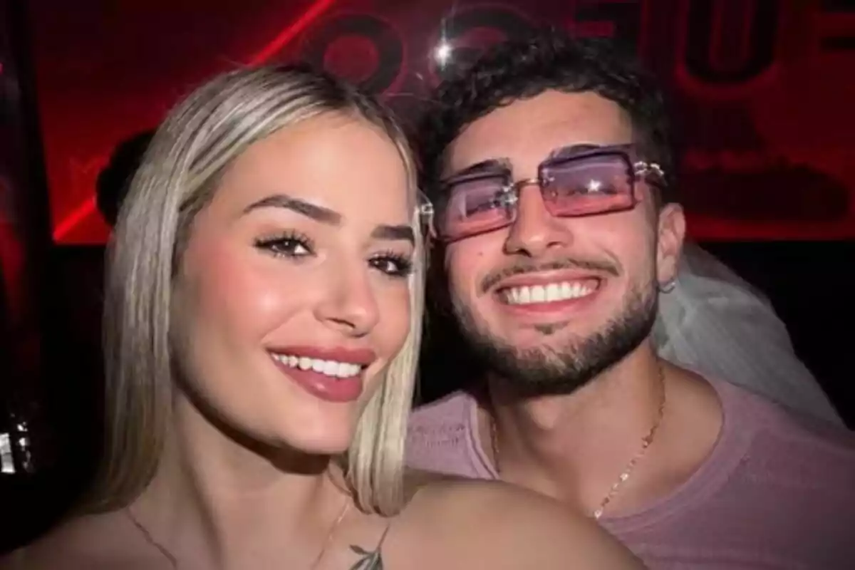 Una pareja joven, formada por Laura Galera y Manu Vulcan, sonríe mientras se toma una selfie en un lugar con luces rojas de fondo. Una pareja joven, formada por Laura Galera y Manu Vulcan, sonríe mientras se toma una selfie en un lugar con luces rojas de fondo.