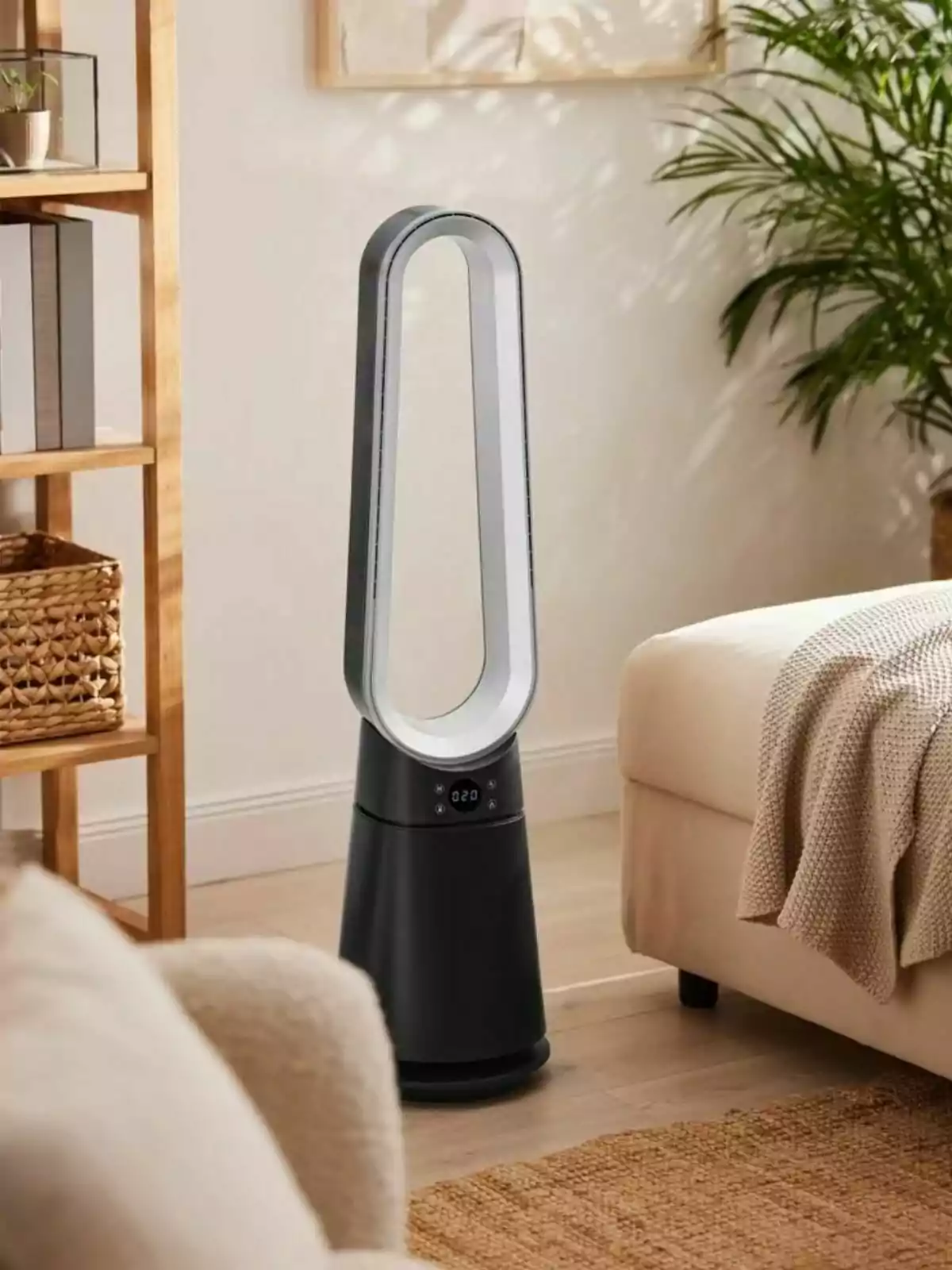Ventilador sin aspas de color negro y plateado colocado en una sala moderna con muebles claros y plantas decorativas Ventilador sin aspas de color negro y plateado colocado en una sala moderna con muebles claros y plantas decorativas