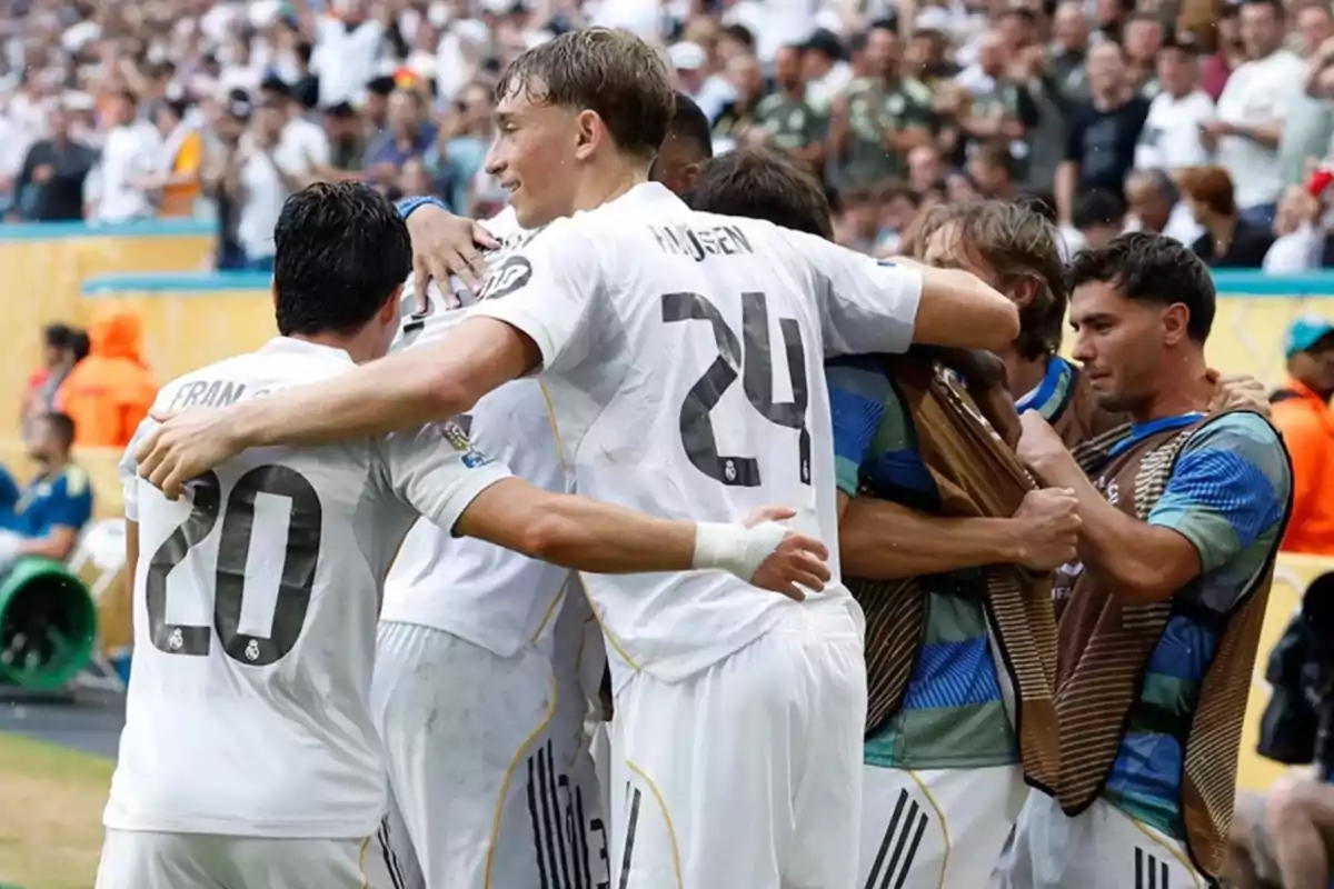 Jugadores de un equipo de fútbol celebran juntos un gol en el campo rodeados de aficionados en las gradas Jugadores de un equipo de fútbol celebran juntos un gol en el campo rodeados de aficionados en las gradas