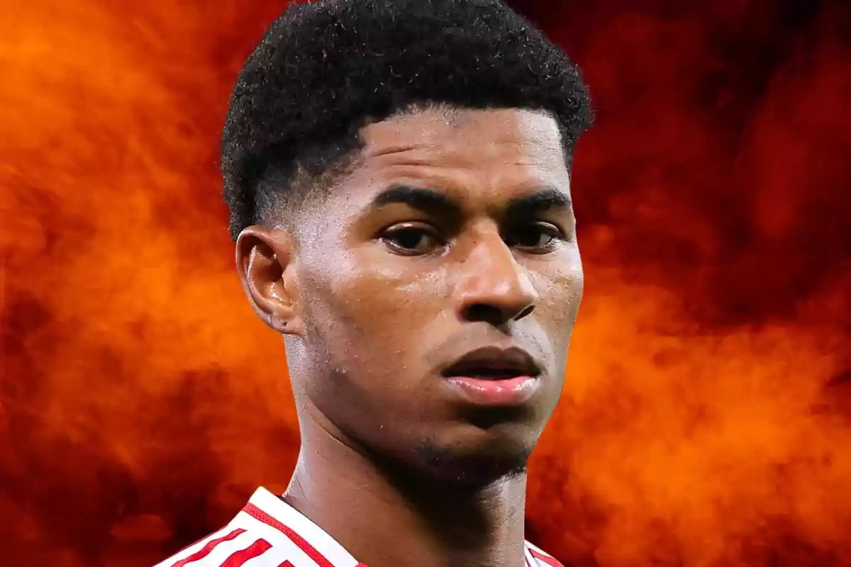 Jugador de fútbol con camiseta blanca y roja sobre un fondo de humo naranja intenso