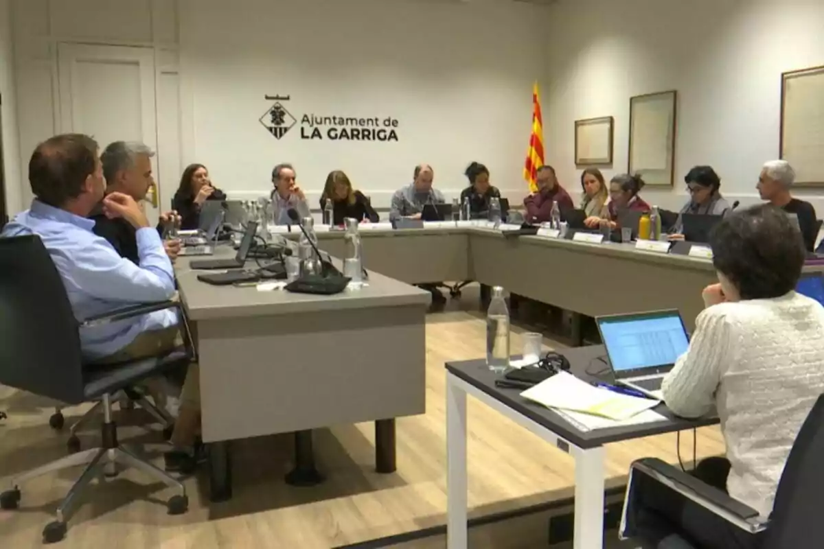 Reunión de varias personas sentadas alrededor de una mesa en una sala de juntas del ayuntamiento de La Garriga con ordenadores portátiles y botellas de agua sobre la mesa Reunión de varias personas sentadas alrededor de una mesa en una sala de juntas del ayuntamiento de La Garriga con ordenadores portátiles y botellas de agua sobre la mesa