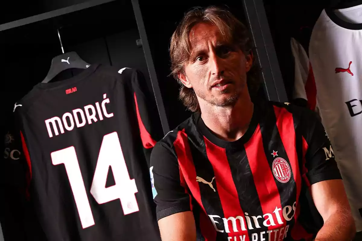Un futbolista con el uniforme del AC Milan está sentado en un vestidor junto a una camiseta colgada con el nombre Modric y el número 14. Un futbolista con el uniforme del AC Milan está sentado en un vestidor junto a una camiseta colgada con el nombre Modric y el número 14.