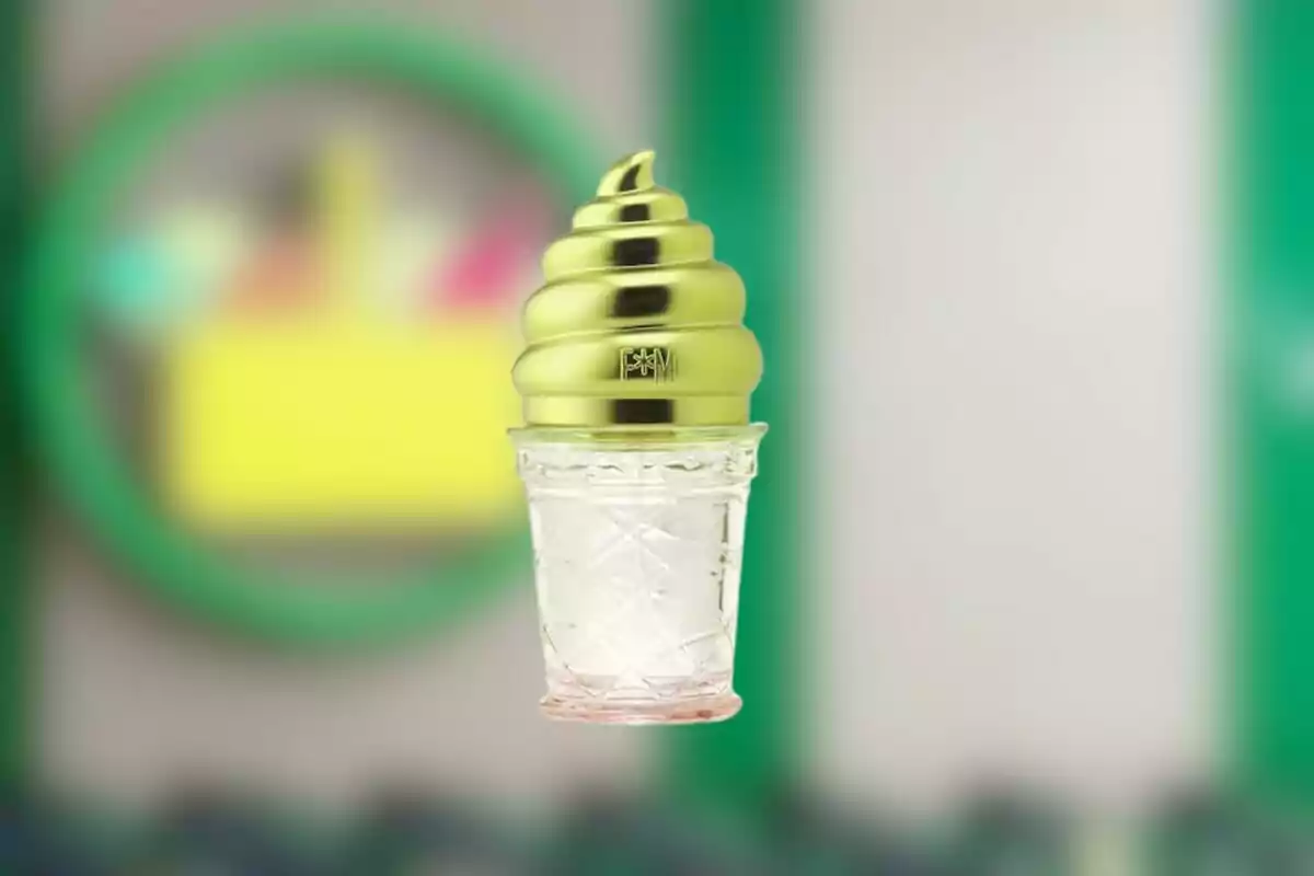 Envase de perfume con forma de cono de helado con tapa dorada y fondo desenfocado Envase de perfume con forma de cono de helado con tapa dorada y fondo desenfocado