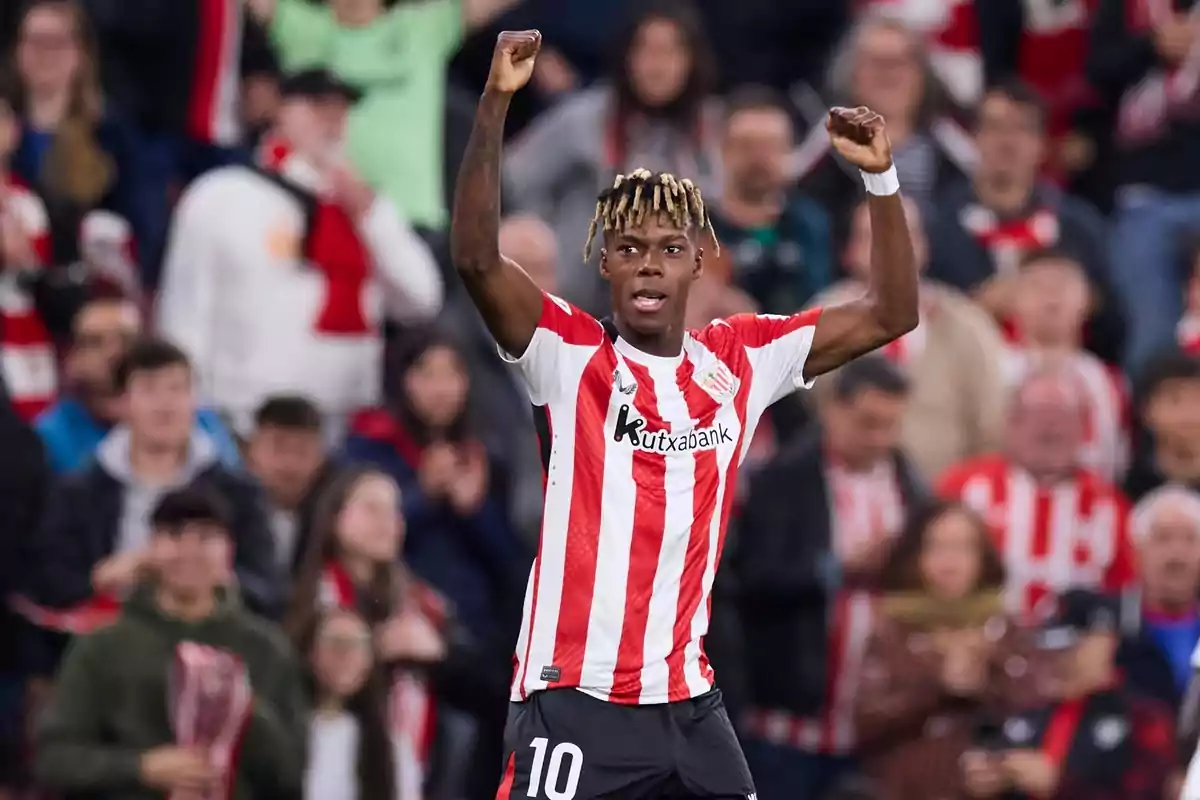 Futbolista del Athletic Club celebrando un gol con los brazos en alto frente a una multitud de aficionados en el estadio Futbolista del Athletic Club celebrando un gol con los brazos en alto frente a una multitud de aficionados en el estadio