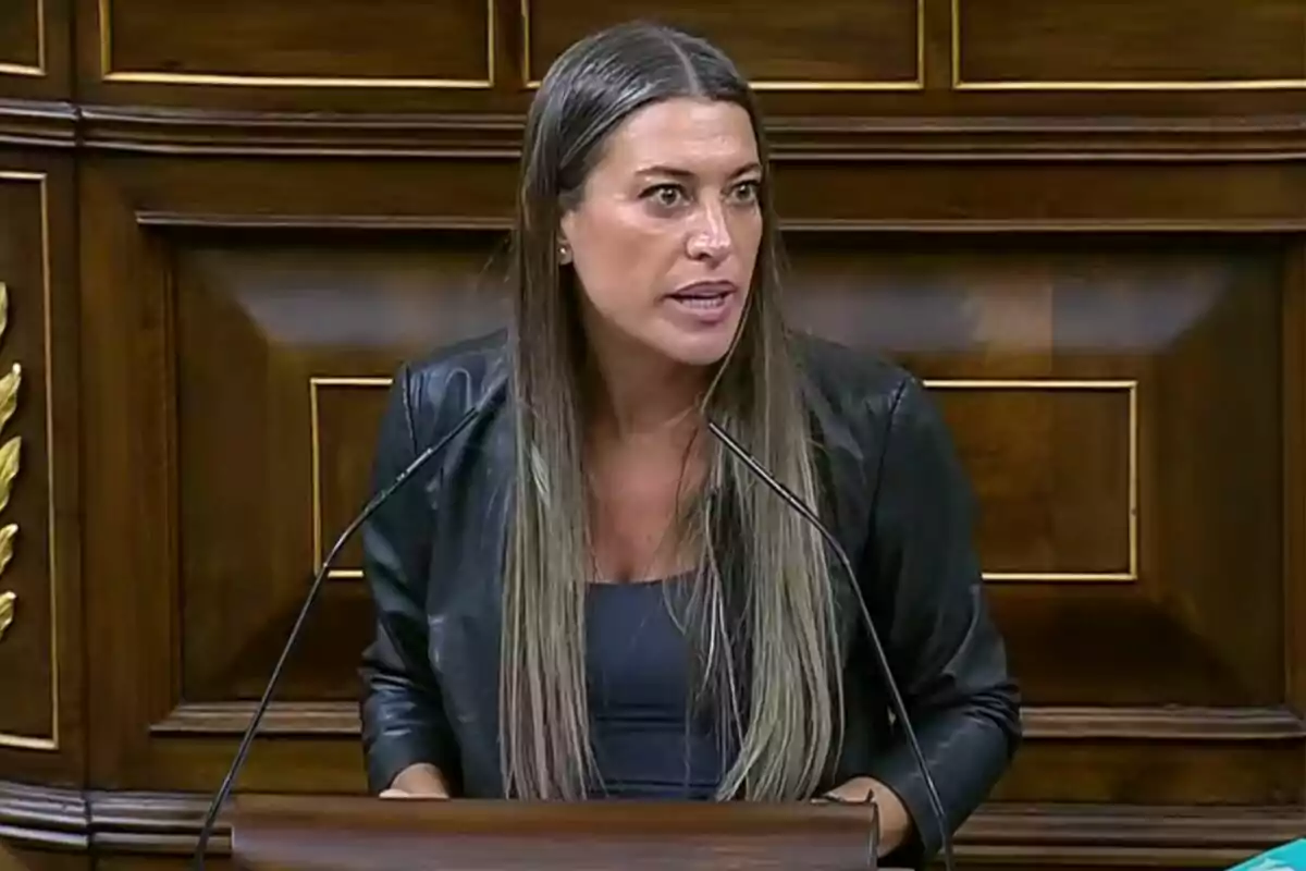 Mujer de cabello largo y liso hablando en un podio de madera con fondo de paneles de madera Mujer de cabello largo y liso hablando en un podio de madera con fondo de paneles de madera