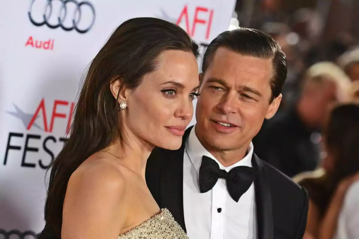 Una pareja elegantemente vestida, formada por Brad Pitt y Angelina Jolie, posa en una alfombra roja durante un evento de gala. Una pareja elegantemente vestida, formada por Brad Pitt y Angelina Jolie, posa en una alfombra roja durante un evento de gala.