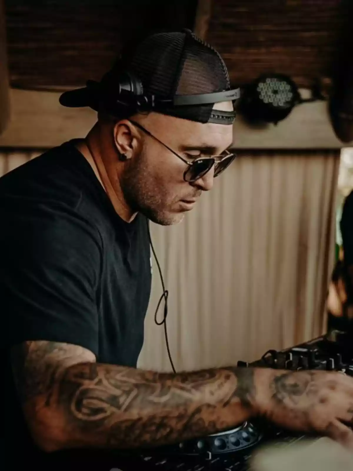 Kiko Rivera con gorra y gafas de sol mezclando música en una consola de DJ Kiko Rivera con gorra y gafas de sol mezclando música en una consola de DJ