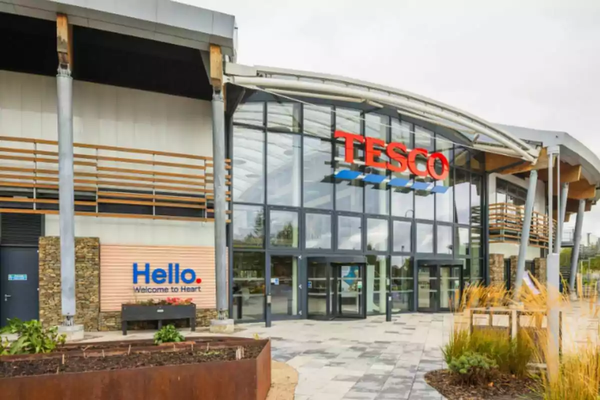 Fachada de una tienda Tesco con entrada principal de vidrio y letrero grande en la parte superior Fachada de una tienda Tesco con entrada principal de vidrio y letrero grande en la parte superior