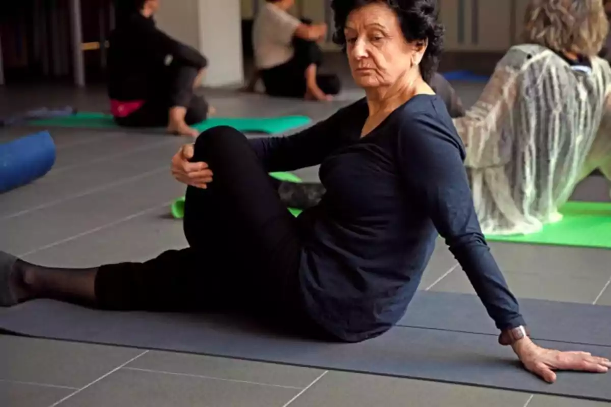 Una mujer mayor practicando yoga en una clase grupal.