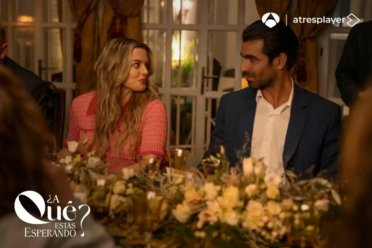 Fotografía de Adriana Torrebejano y Rubén Cortada sentados en una mesa decorada con flores y velas, mirándose mutuamente con expresiones de interés en la serie ¿A qué estás esperando?