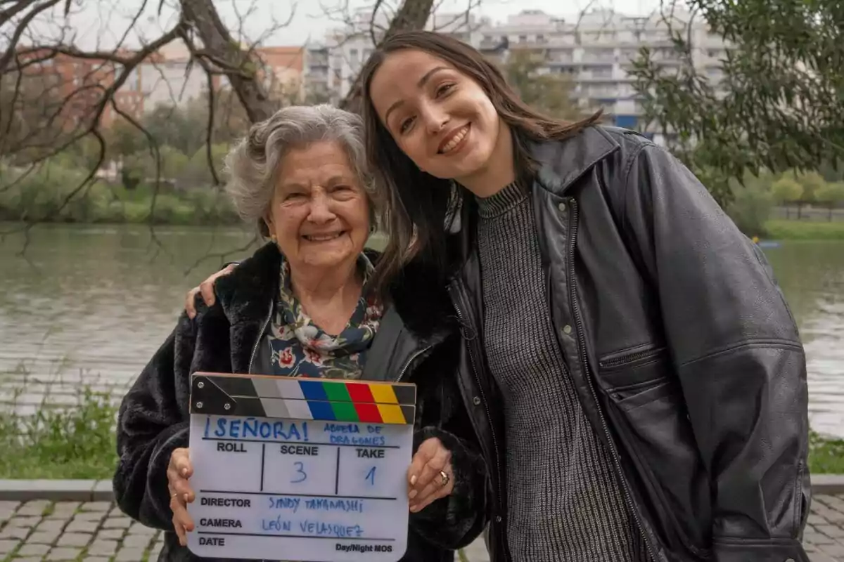 Abuela de dragones y Sindy Takanashi sonríen juntas al aire libre mientras sostienen una claqueta de cine de ¡Señora!. Abuela de dragones y Sindy Takanashi sonríen juntas al aire libre mientras sostienen una claqueta de cine de ¡Señora!.