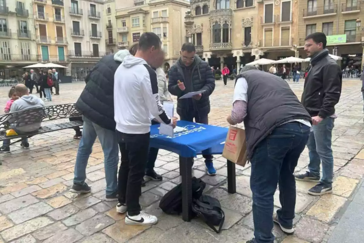 Varias personas alrededor de una mesa de Aliança Catalana firmando avales para el partido de Sílvia Orriols