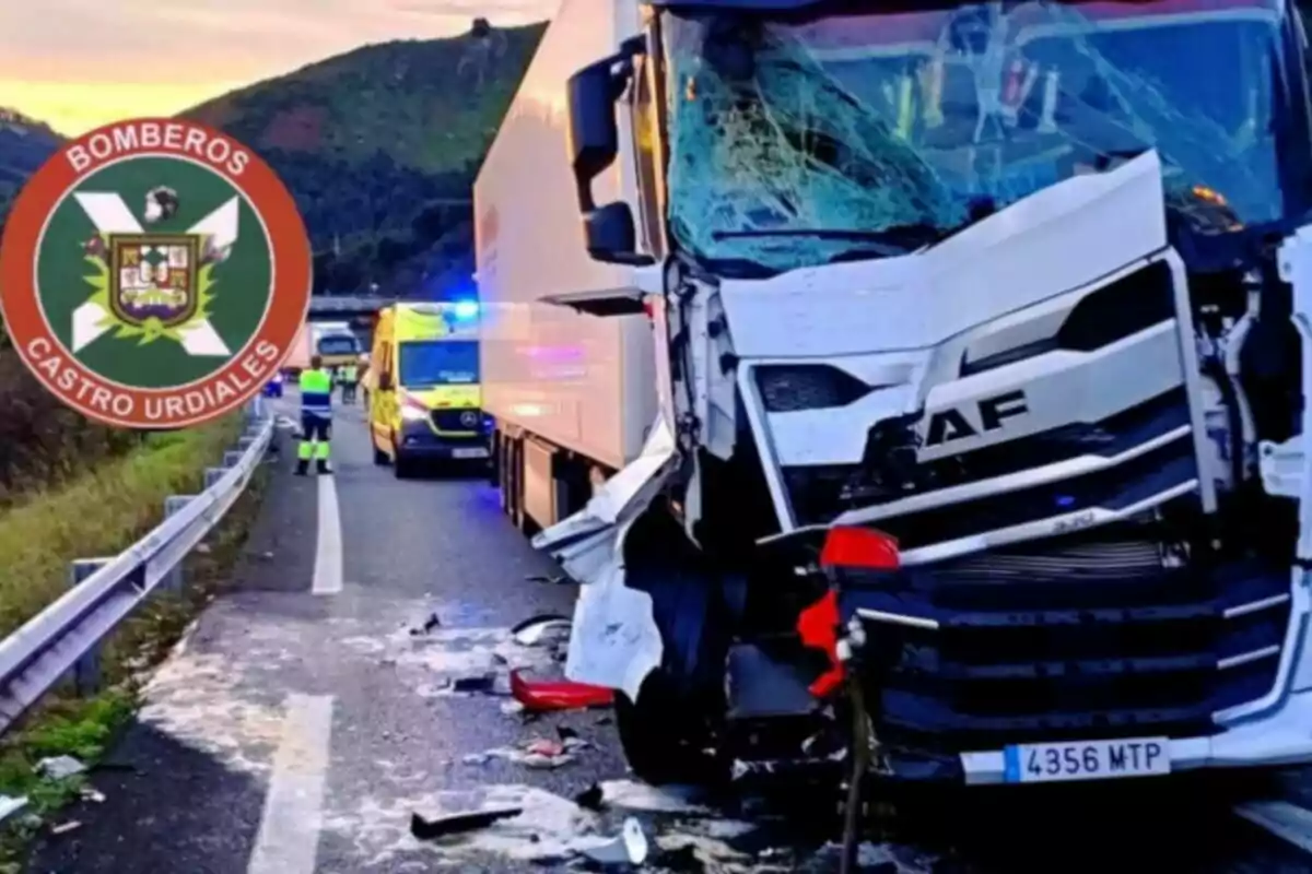 Camión con la parte delantera dañada tras un accidente en una carretera, con presencia de servicios de emergencia y un logotipo de Bomberos Castro Urdiales.