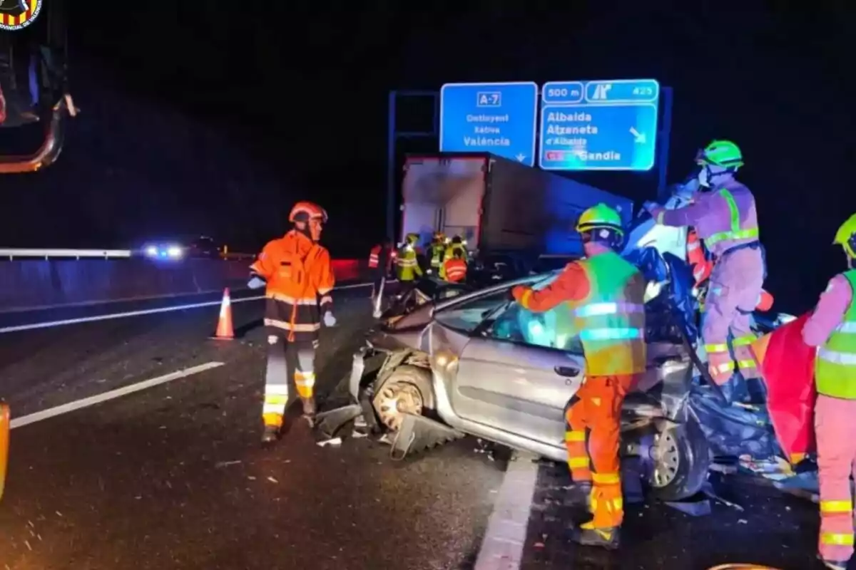 Accidente de tráfico nocturno en una autopista con personal de emergencia trabajando en el lugar.