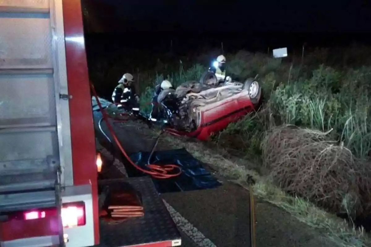 Accidente con un coche del revés y los bomberos actuando en el coche