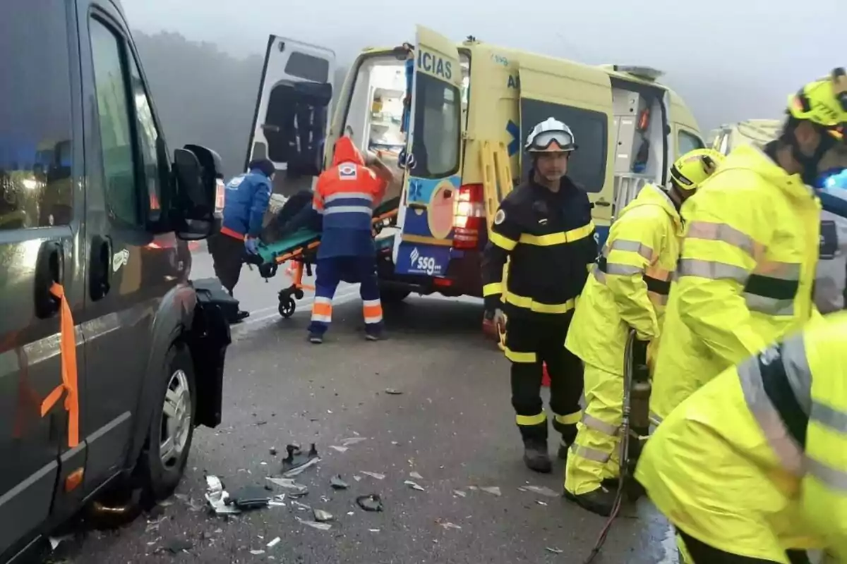 Un grupo de rescatistas y personal médico atiende una emergencia en la carretera junto a una ambulancia y un vehículo dañado.