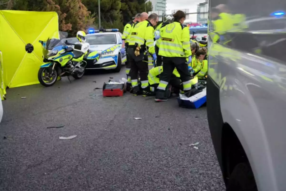 Un grupo de paramédicos atiende una emergencia en una carretera, rodeados de vehículos de policía y una motocicleta.