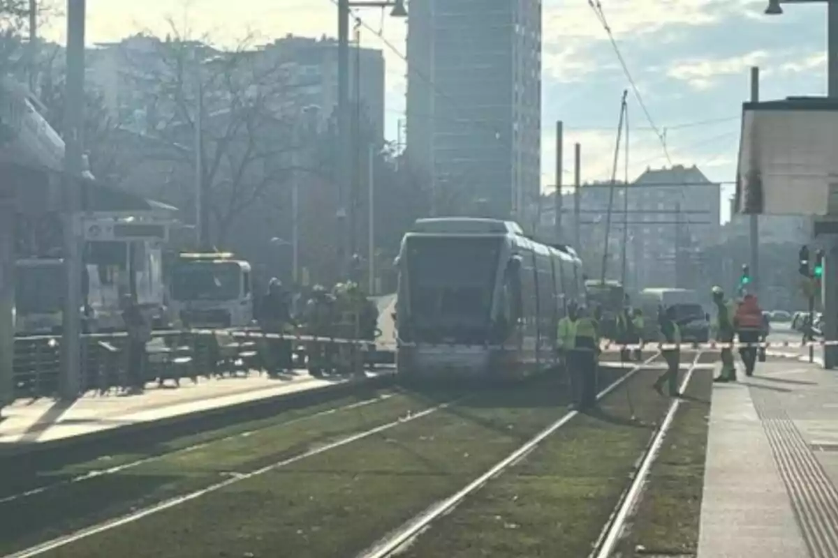 Un tranvía detenido en una vía con trabajadores alrededor en una ciudad.