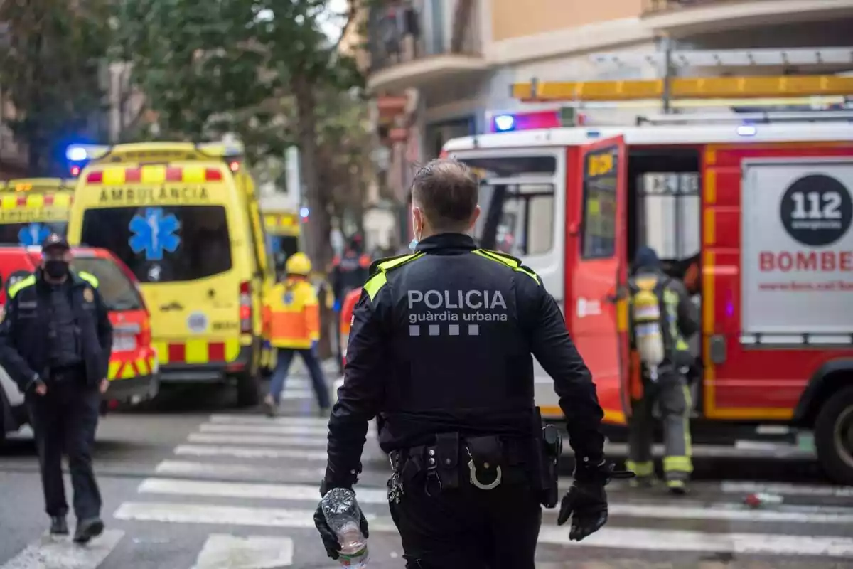 Fotomontaje de un agente de la Guàrdia Urbana, con varias ambulancias y una dotación de los Bomberos de la Generalitat