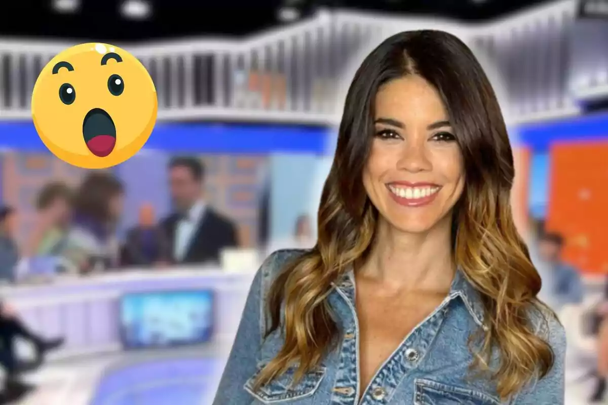 Una mujer sonriente con cabello largo y ondulado lleva una chaqueta de mezclilla en un estudio de televisión con un emoji sorprendido en la esquina.