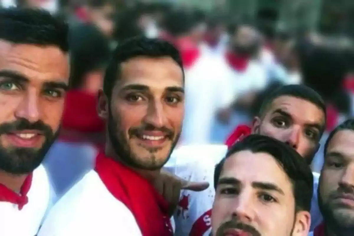 Cinco hombres jóvenes posan para una selfie vistiendo camisetas blancas y pañuelos rojos en un ambiente festivo. Cinco hombres jóvenes posan para una selfie vistiendo camisetas blancas y pañuelos rojos en un ambiente festivo.