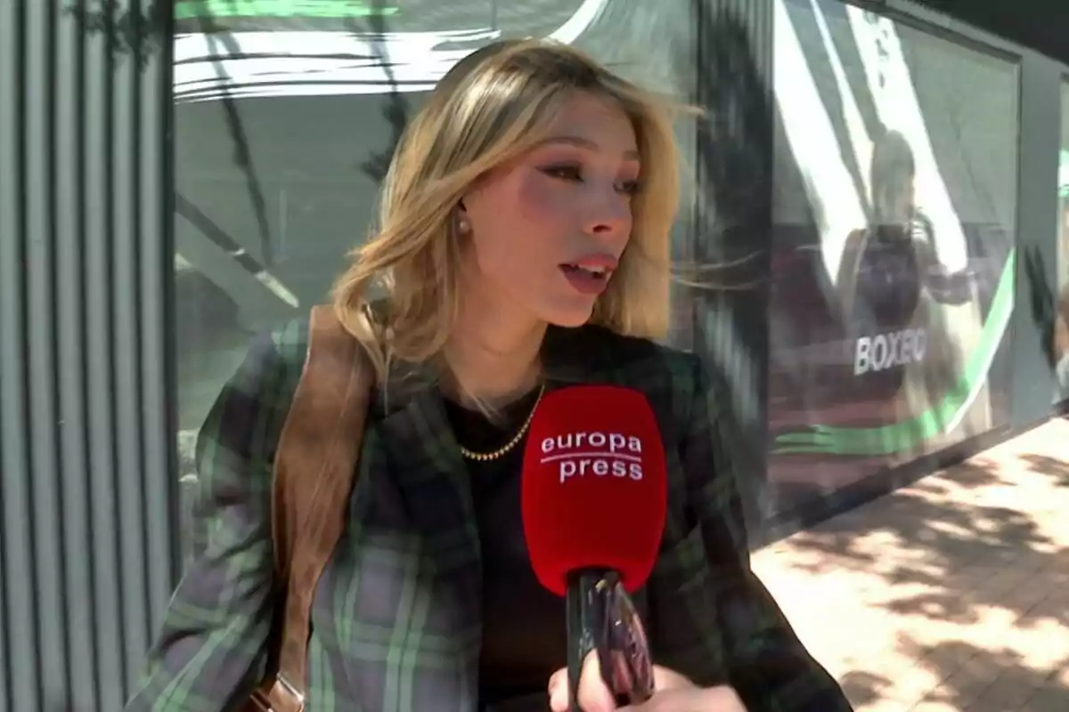 Alejandra Rubio siendo entrevistada por un medio de comunicación con un micrófono rojo que dice Alejandra Rubio siendo entrevistada por un medio de comunicación con un micrófono rojo que dice