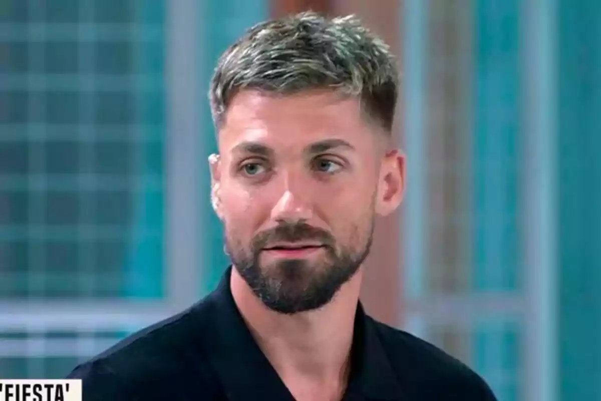 Captura de Alejandro Albalá con barba y cabello corto rubio oscuro, vistiendo una camisa negra, en Fiesta