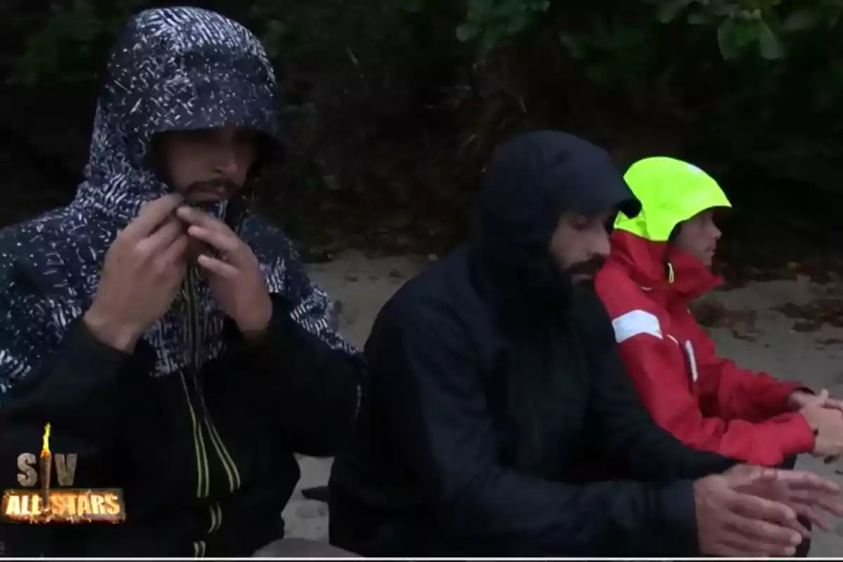 Fotografía de Alejandro Nieto, Jorge Pérez y Bosco Martínez Bordiú con chubasqueros debajo de la lluvia de Supervivientes