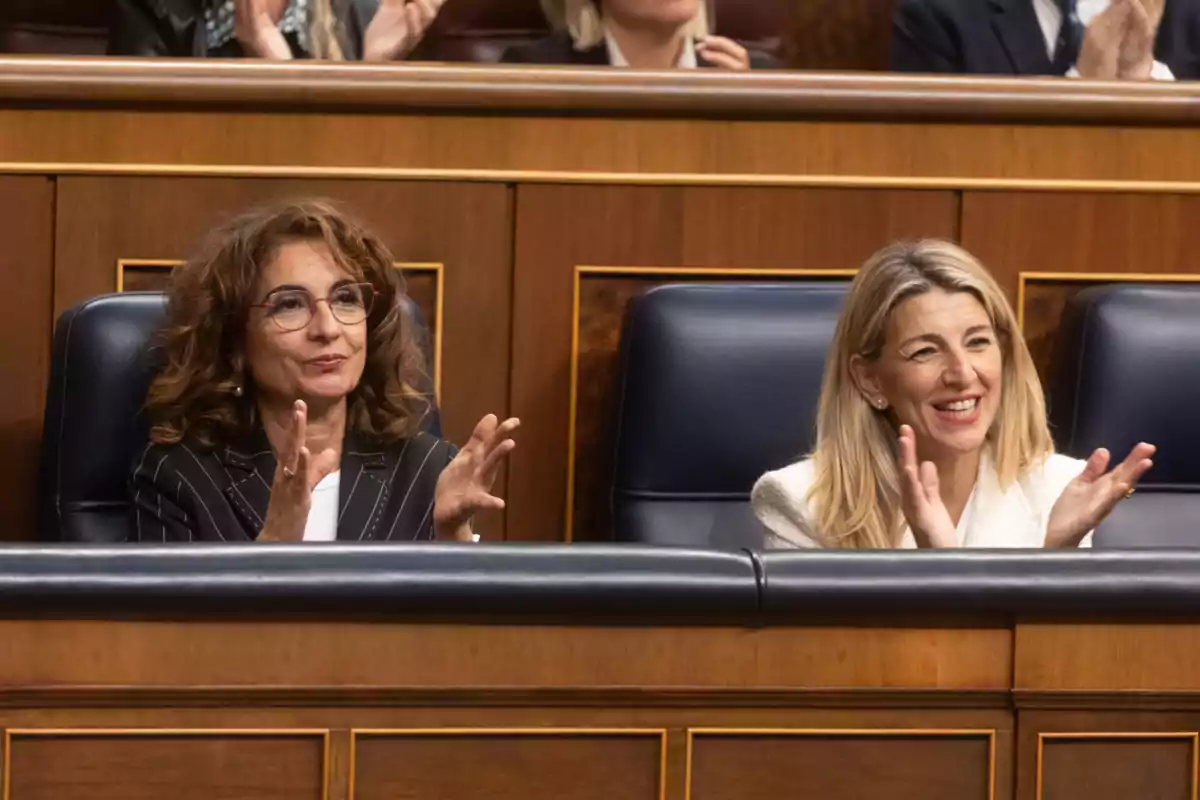 María Jesús Montero y Yolanda Díaz aplaudiendo sentadas en un parlamento.