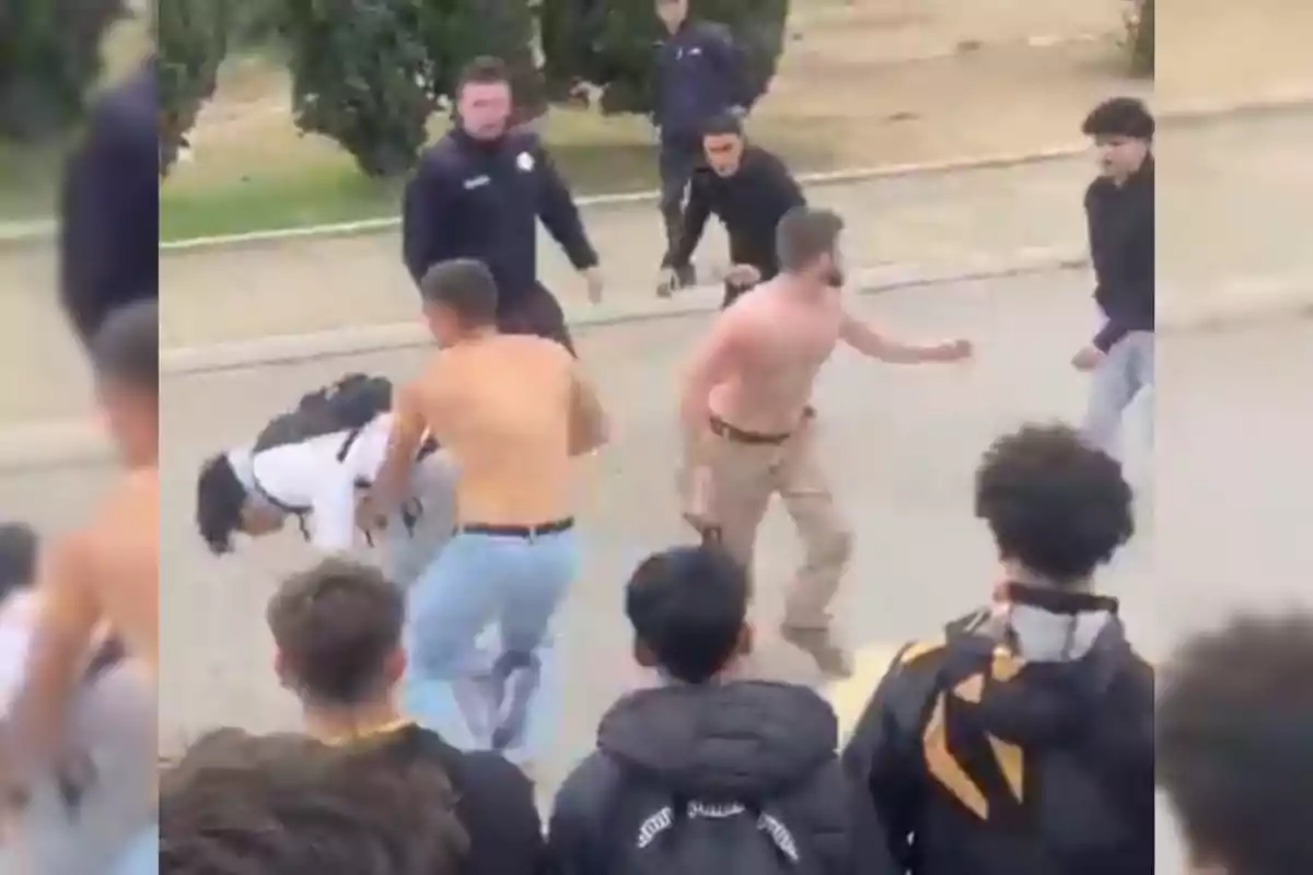 Un grupo de personas en una confrontación en un espacio al aire libre con espectadores alrededor.