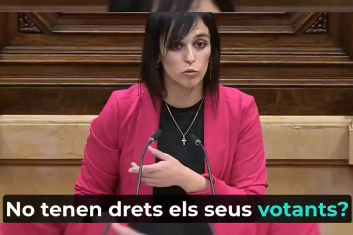 Mujer hablando en un podio con un texto en catalán que dice "No tenen drets els seus votants?"