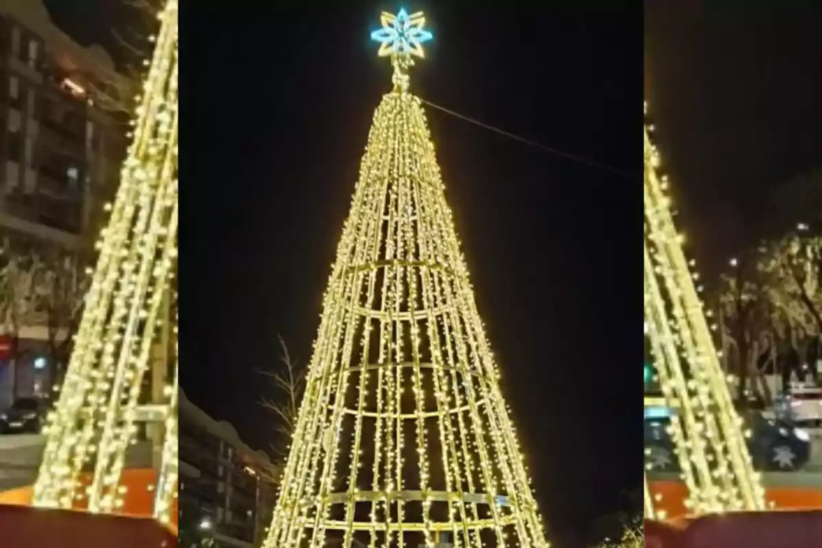 Árbol de Navidad iluminado con luces doradas en una calle por la noche.